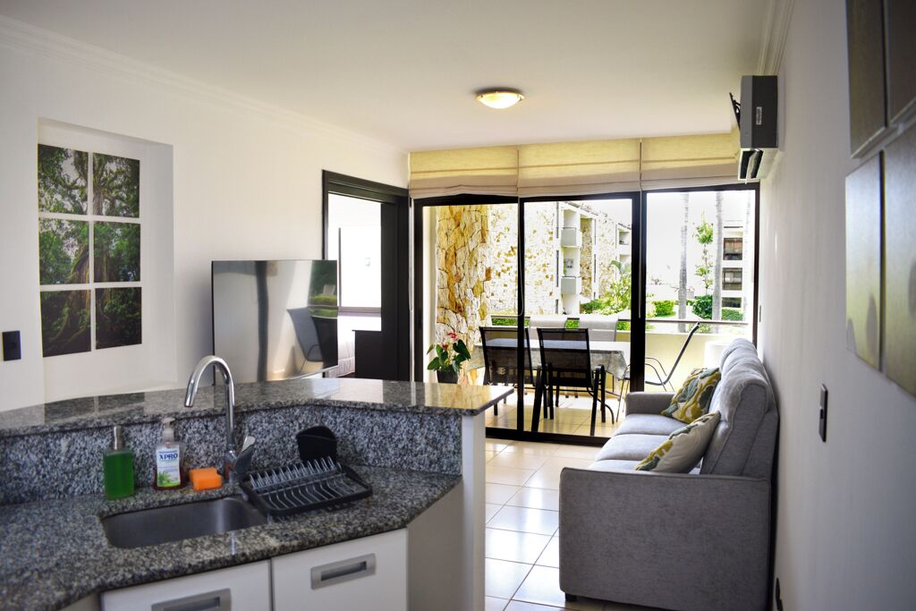 Een moderne keuken met granieten aanrechtbladen, een inbouwspoelbak en een eethoek met een tafel en stoelen.