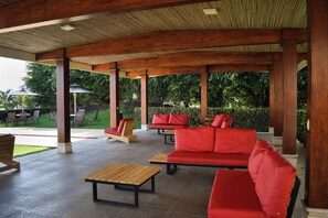 An outdoor covered patio area with wooden furniture and red cushions. - Aparmet, 2 bedrooms, gym, pool, restaurant, tennis, hot tub, Rio Oro de Santa Ana (Río Oro)