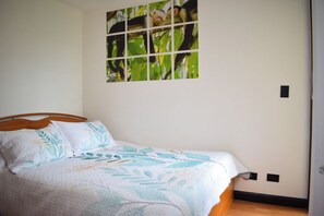 A bedroom with a bed, a wall-mounted picture of monkeys, and a door. - Aparmet, 2 bedrooms, gym, pool, restaurant, tennis, hot tub, Rio Oro de Santa Ana (Río Oro)