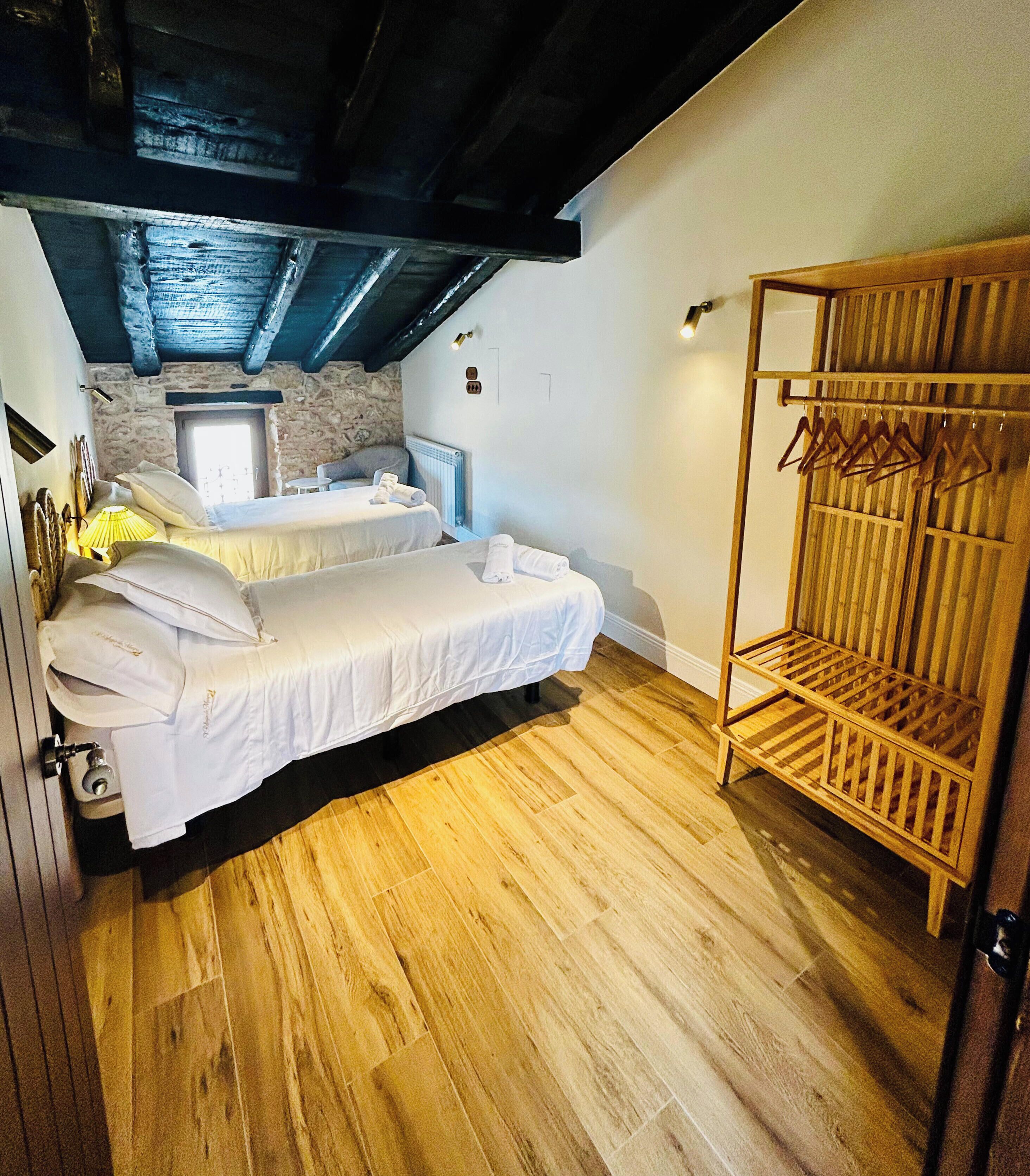 A bedroom with a bed, a wooden bench, and a stone wall.