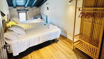 A bedroom with a bed, a wooden bench, and a stone wall.