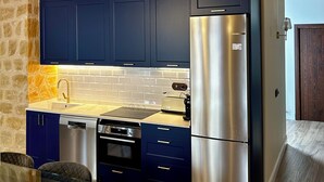 Uma cozinha moderna com armários azul escuro, eletrodomésticos de aço inoxidável e uma parede de pedra.