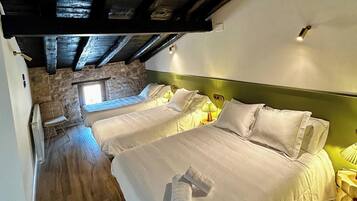 A hotel room with two beds, a stone wall, and a wooden ceiling.