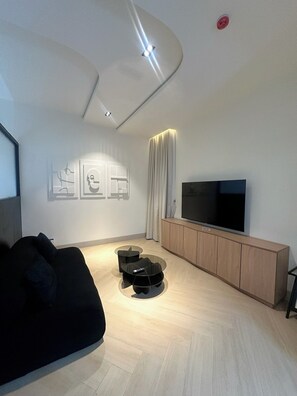 Uma sala de estar moderna com uma TV de tela plana, um sofá, uma mesa de centro e um armário.