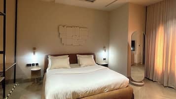 Ein modernes Hotelzimmer mit einem großen Bett, einem Spiegel, einer Wandleuchte und einer Deckenlampe.
