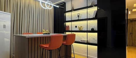 A modern kitchen with a bar area, wooden flooring, and pendant lighting.
