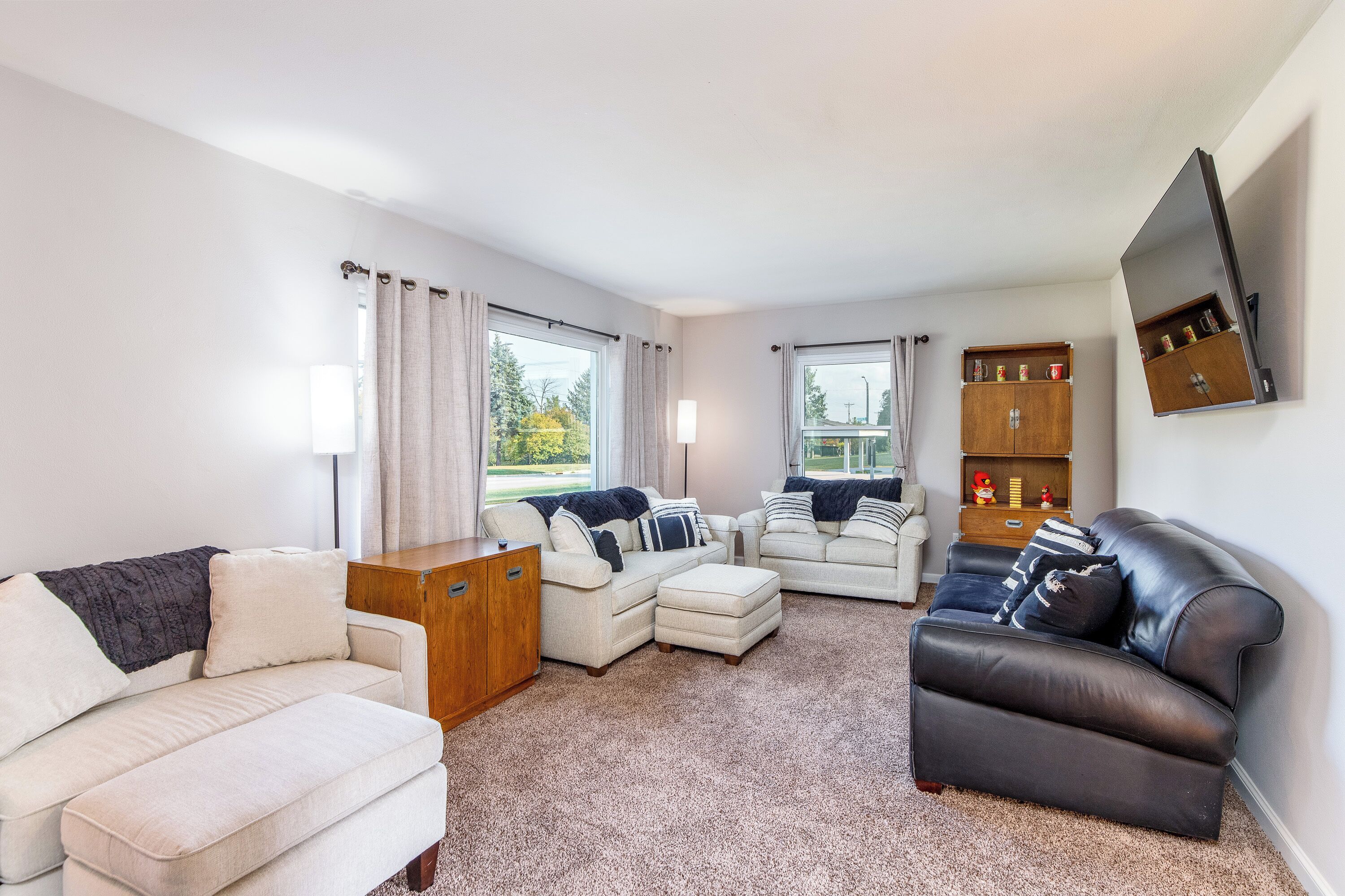 A living room with a sofa set, a coffee table, and a television mounted on the wall.