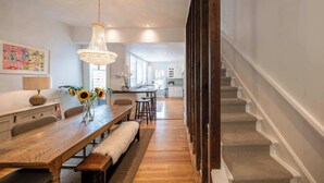 A dining area with a wooden table, benches, and a chandelier. - Charming Victorian Home | Little Italy + Garden (Toronto)