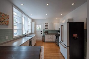 Une cuisine moderne dotée d’un grand îlot central, de meubles blancs et d’un réfrigérateur noir.