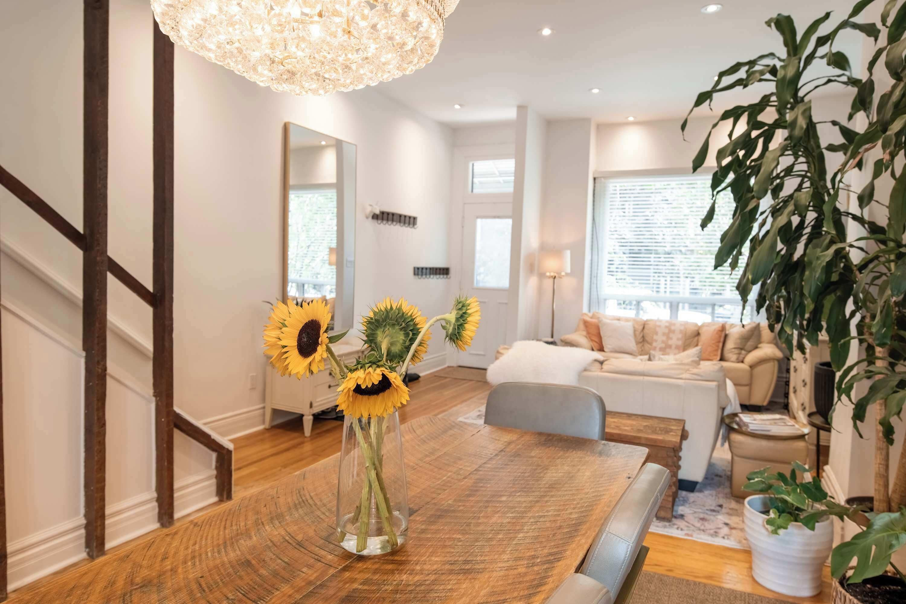 Una sala de estar moderna con comedor, una escalera y un ventanal grande.