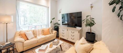 A living room with a sofa, coffee table, TV, and plants.