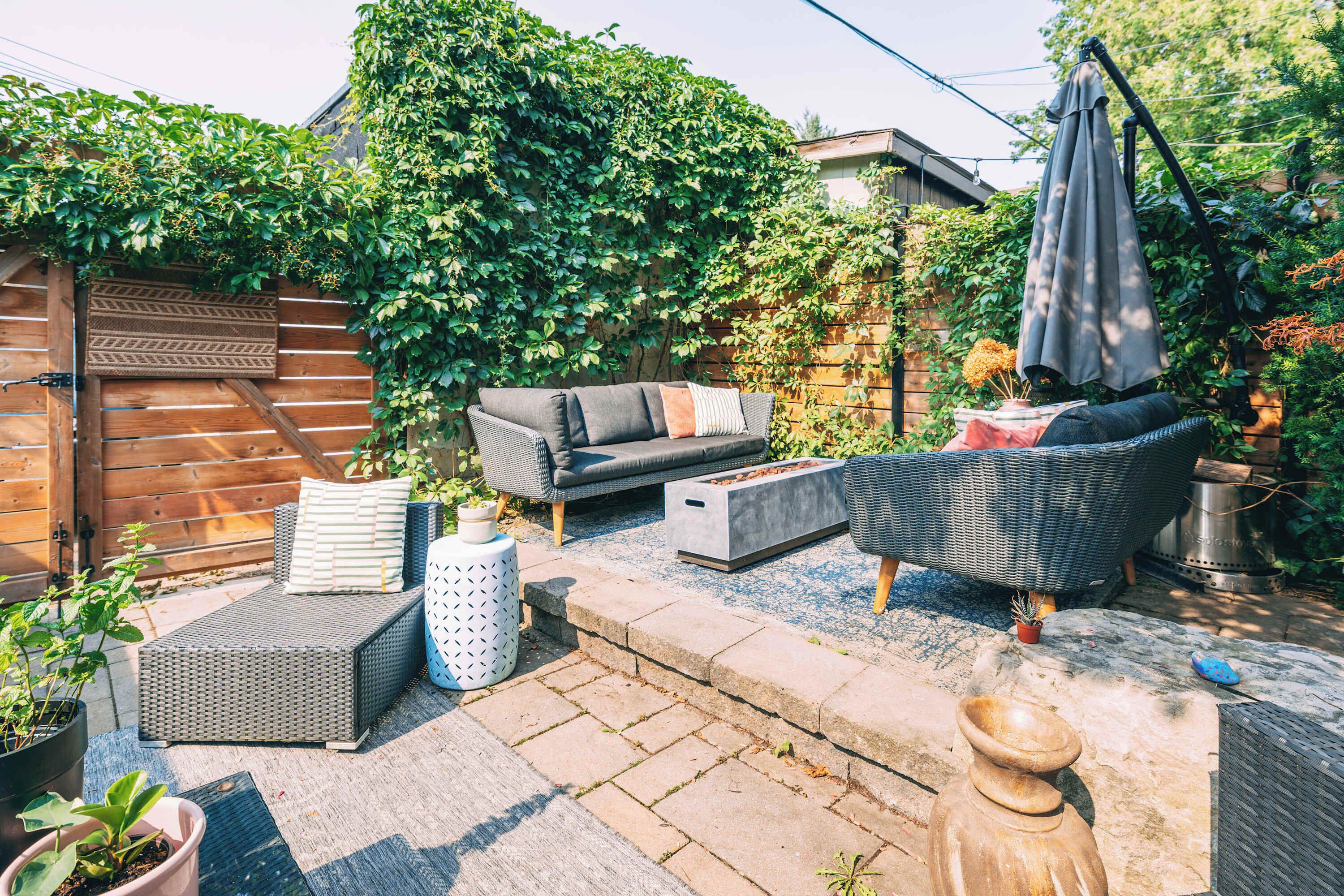 Une terrasse avec des meubles d’extérieur, une clôture en bois et un jardin.
