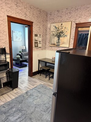 A kitchen with a refrigerator, a dining table with chairs, a trash bin, and a microwave. - SMOKE FRIENDLY Lovely 1-bedroom apartment with AC in vibrant Racine (Racine)