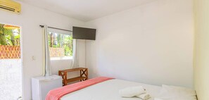 A bedroom with a bed, a desk, a television, and an air conditioning unit. - Suite Quadrupla a 400m da Praia de Itamambuca (Ubatuba)