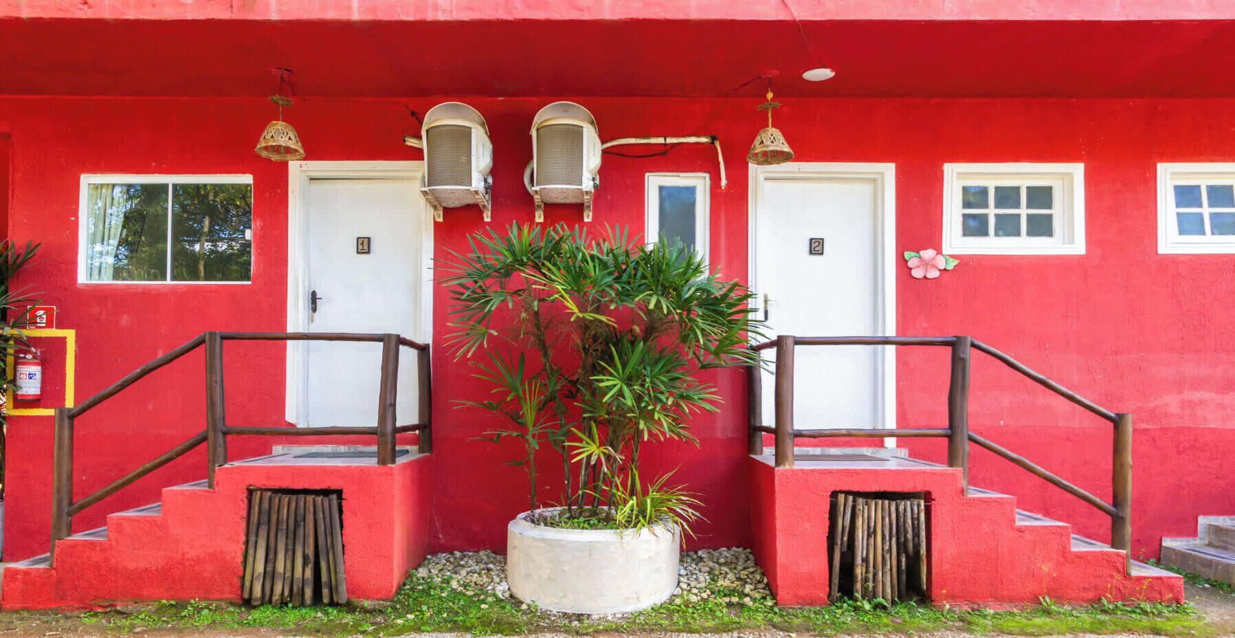 Ein rotes Gebäude mit zwei Türen, einer Treppe und einem Blumentopf.
