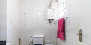A bathroom with a toilet, a towel rack with a towel, and a water heater. - Apartamento no Rio de Janeiro ao lado do Maracanã (Rio de Janeiro)