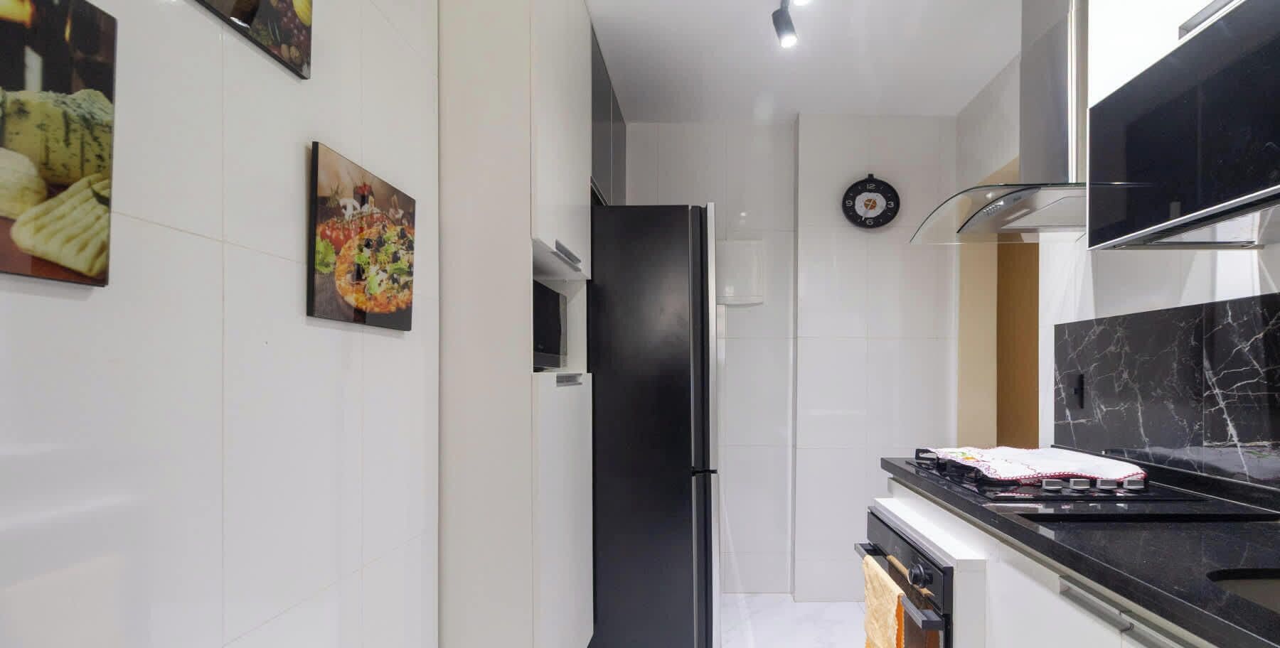 Une cuisine moderne avec des meubles blancs, un réfrigérateur noir et un pare-feu en marbre.