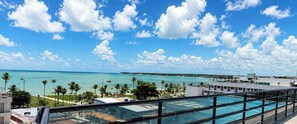 A poolside view with a clear sky and a distant beach. - Flat em Joao Pessoa a 50m da Praia de Tambau (João Pessoa)