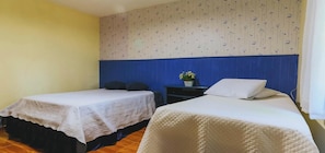 A room with two beds, a small table with a plant, and a wall with a floral pattern. - Sitio em Campinas com Piscina e Churrasqueira (Campinas)