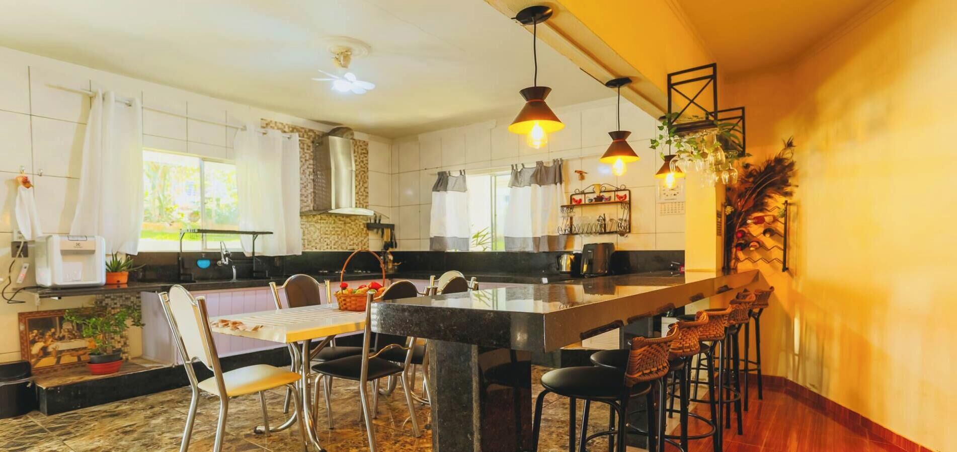 A modern kitchen with a central island, bar stools, and pendant lighting.