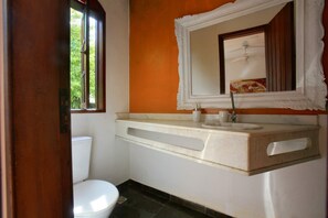 Ein Badezimmer mit Toilette, Waschbecken, Spiegel und Fenster.