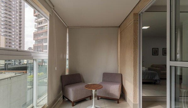 A balcony with two armchairs and a small round table, overlooking a cityscape. - Studio em Sao Paulo a 50m do Vila Nova Star (São Paulo)