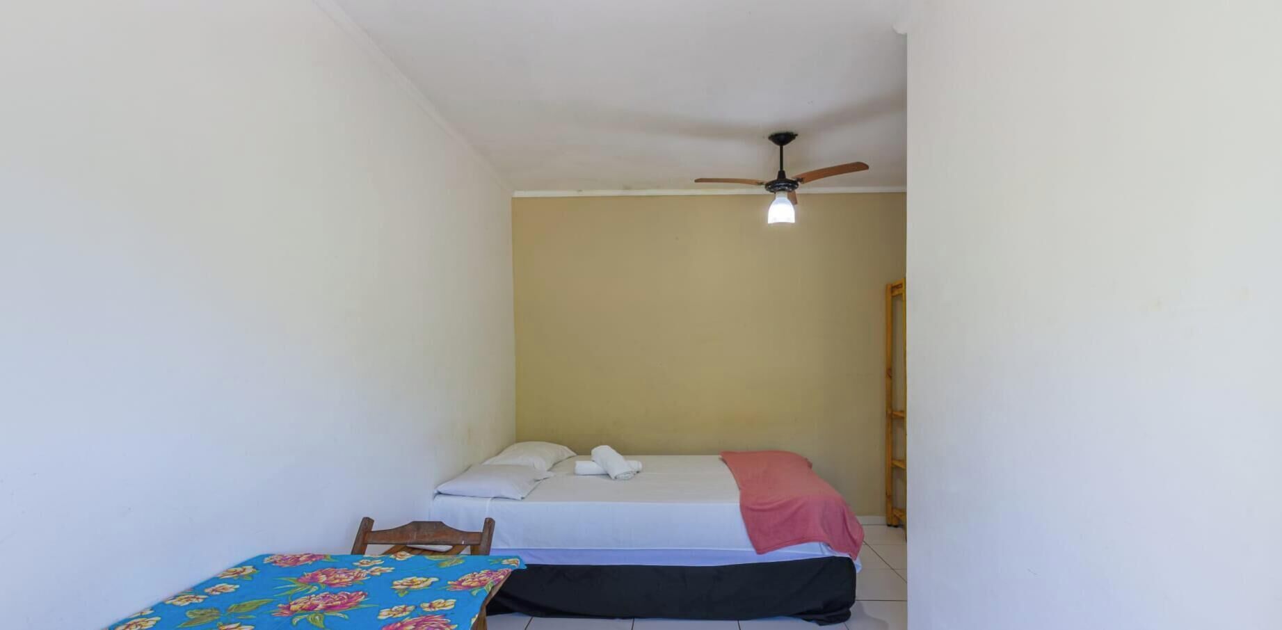 A small, single-room accommodation with a bed, a chair, and a table.