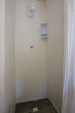 A small, enclosed shower area with white tiles and a drain. - Suíte Dupla em Buzios Perto da Rua das Pedras (Armação dos Búzios)