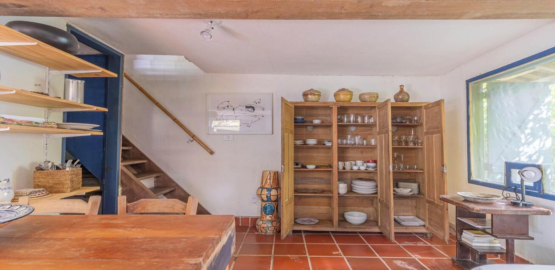 Una cocina con estantes de madera, una mesa de comedor y una escalera.
