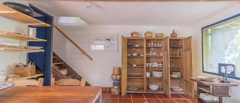 Una cocina con estantes de madera, una mesa de comedor y una escalera.
