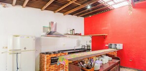 Cozinha com fogão a gás, geladeira e parede vermelha.