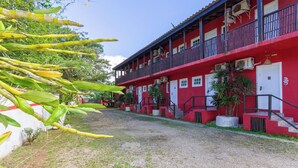 Un edificio rosso con diversi balconi e un vialetto sterrato.
