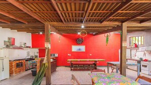 Una cucina con una parete rossa, travi in legno a soffitto e un'area pranzo con tavolo e sedie.