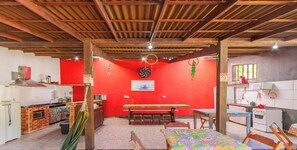 Eine Küche mit roter Wand, Holzbalken an der Decke und einem Essbereich mit Tisch und Stühlen.