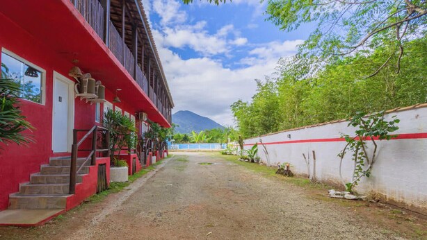 Un edificio rosso con una scalinata che conduce all'ingresso, circondato da vegetazione e un cielo sereno.