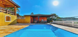 A swimming pool with a covered area, a patio, and a building with a red roof. - Sitio em Atibaia com piscina e churrasqueira (Atibaia)
