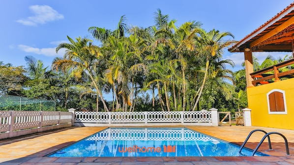 A swimming pool with a white fence and palm trees in the background. - Sitio em Atibaia com piscina e churrasqueira (Atibaia)