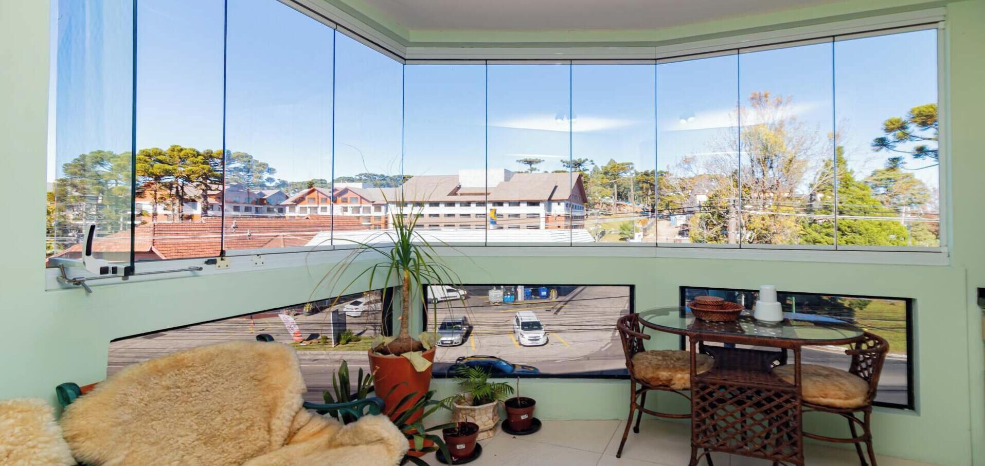 A room with a large bay window, a dining table with chairs, and potted plants.