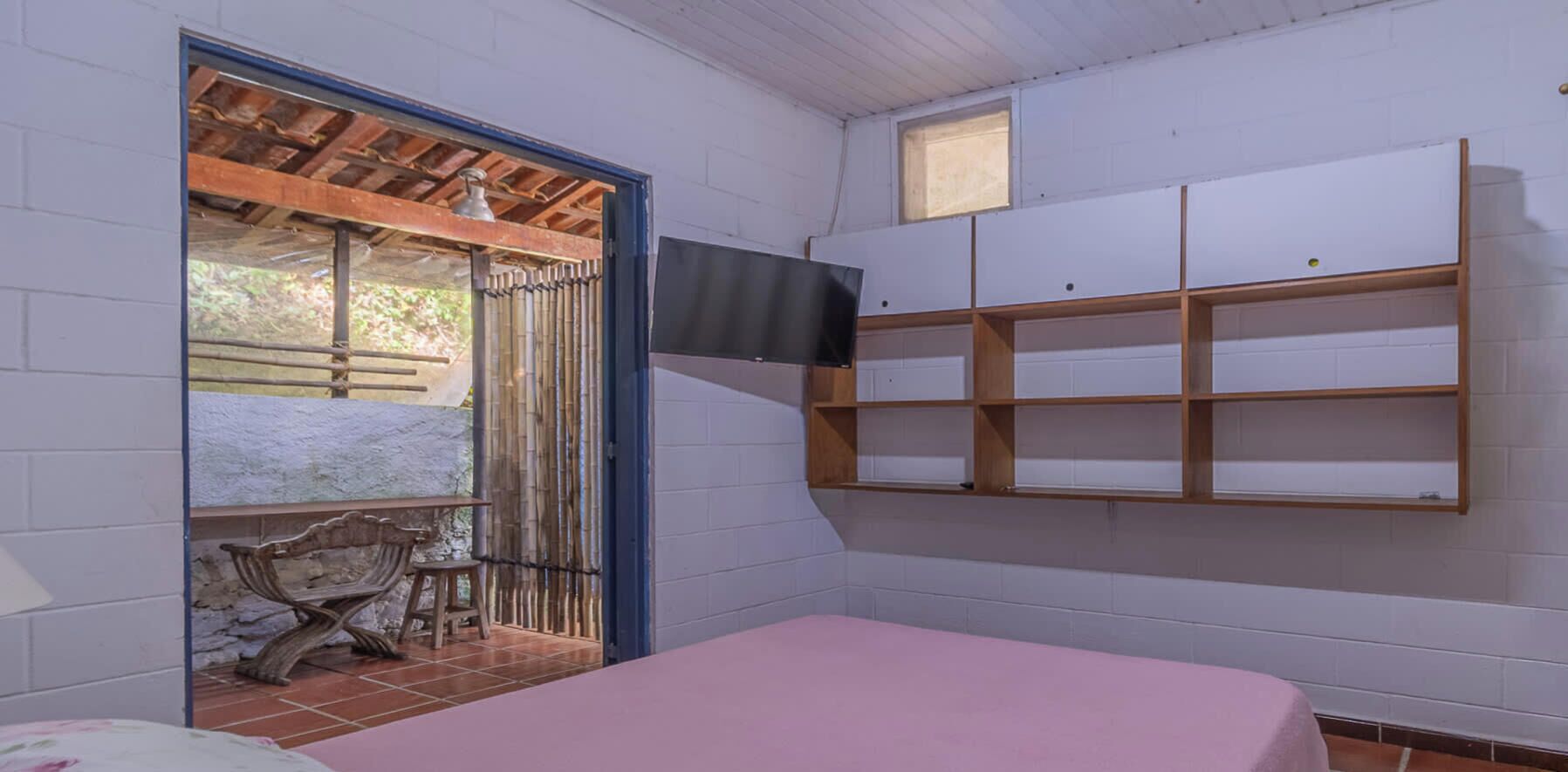 Una habitación con cama, televisión montada en la pared y ventana con vistas al exterior.