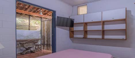 Una habitación con cama, televisión montada en la pared y ventana con vistas al exterior.