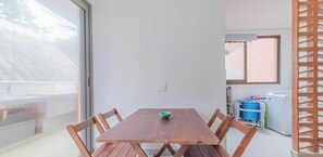 A dining area with a wooden table and chairs, a bowl on the table, and a view of a balcony with a railing. - Casa em Sao Sebastiao Frente a Praia com Vista (sao sebastiao)