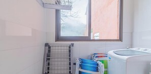 A laundry room with a drying rack, stacked laundry baskets, and a washing machine. - Casa em Sao Sebastiao Frente a Praia com Vista (sao sebastiao)