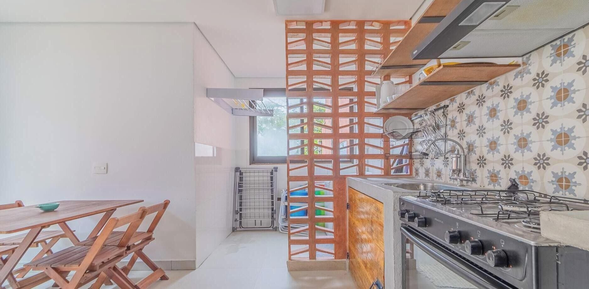 A kitchen with a gas stove, a wooden dining table with chairs, and a decorative partition.