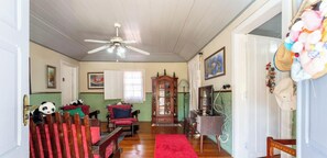 A spacious living room with a wooden floor, a ceiling fan, a red rug, and a large wooden cabinet. - Casa Charmosa em Miguel Pereira com Churrasqueira (Miguel Pereira)