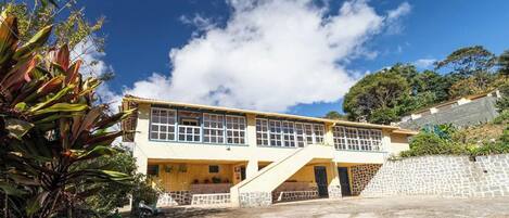 A two-story building with a flat roof, large windows, and a stone wall.