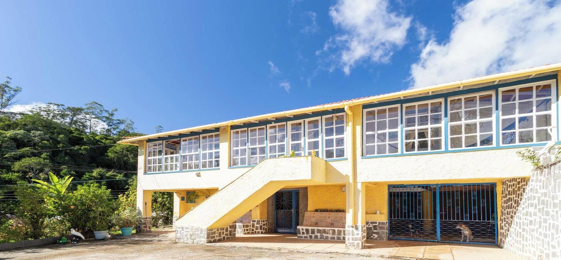 A two-story building with a staircase leading to the upper floor, large windows, and a covered outdoor area.