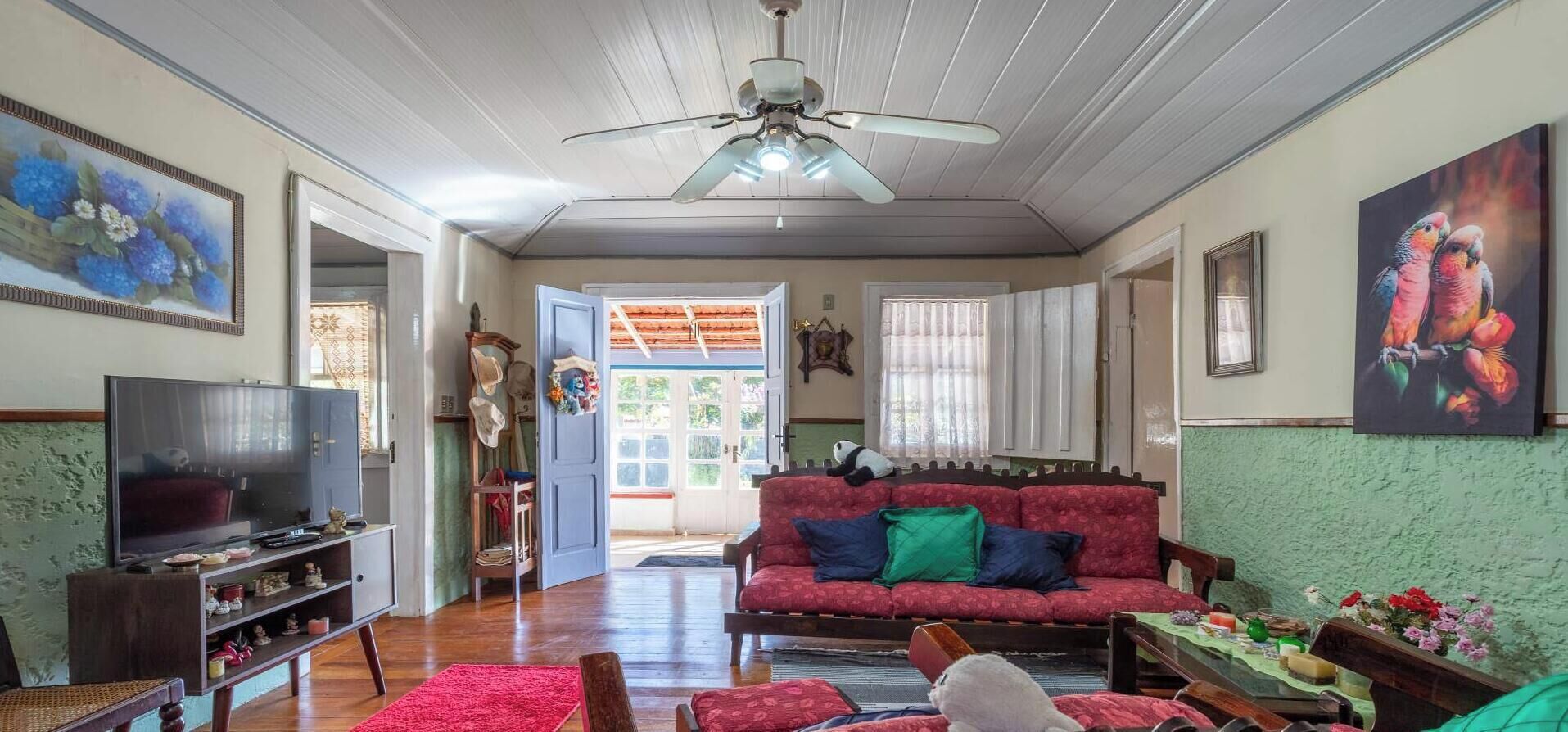 A living room with a television, sofa, and a ceiling fan.