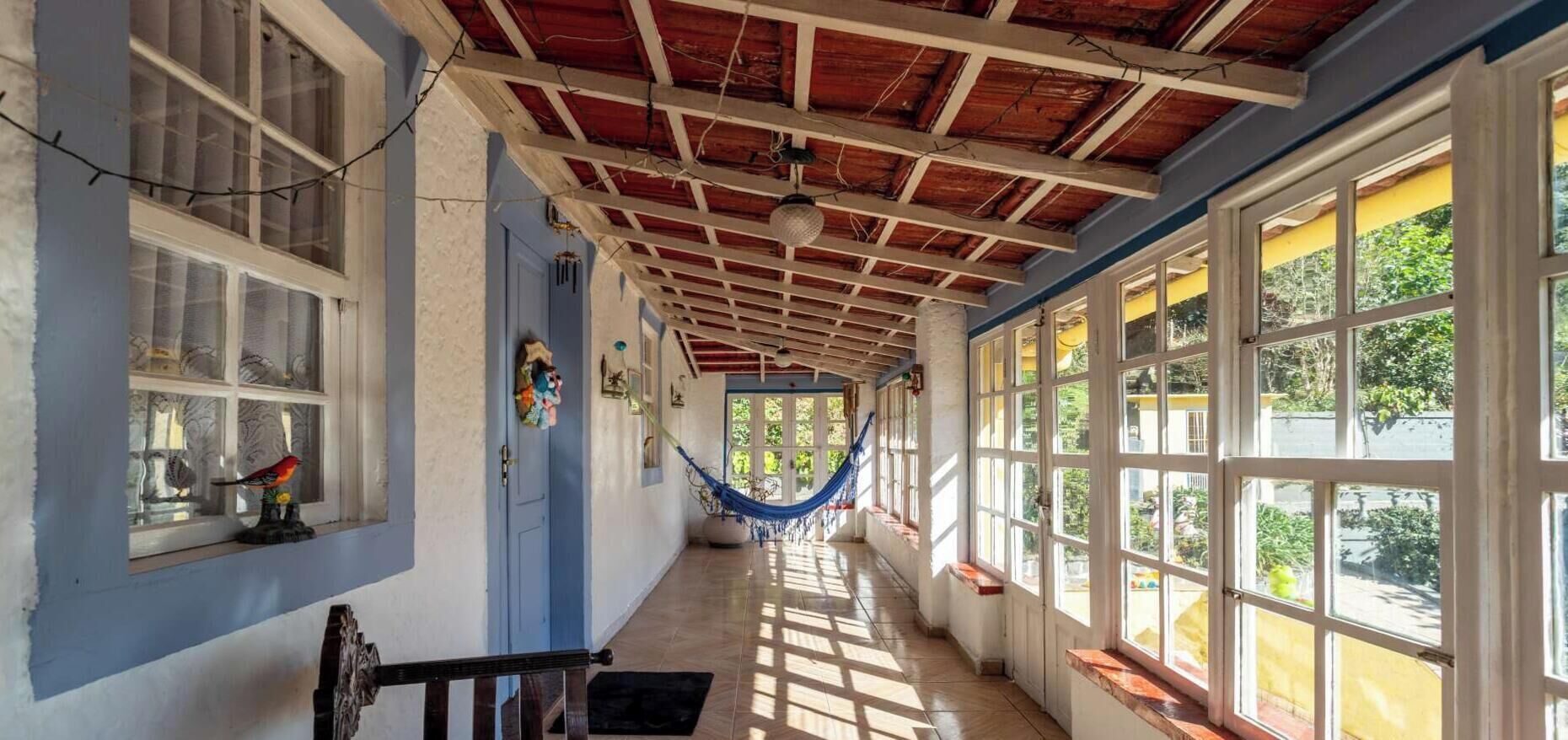 Un couloir avec un plafond en bois, de grandes fenêtres et un hamac.