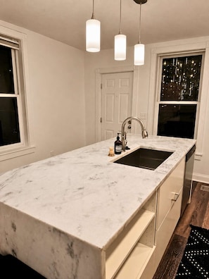 A kitchen with a white marble countertop, a stainless steel sink, and pendant lighting. - Cozy Cabana by Jungle House | Downtown & Short North | Free Parking | Near Convention Center & OSU (Columbus)