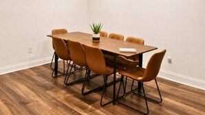 Una sala conferenze con un tavolo di legno, sei sedie e una pianta in vaso.